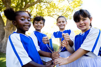 Happy children soccer team holding cup