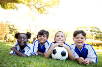 children soccer team smiling at camera while lying on the floor