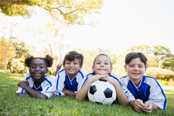 children soccer team smiling at camera while lying on the floor